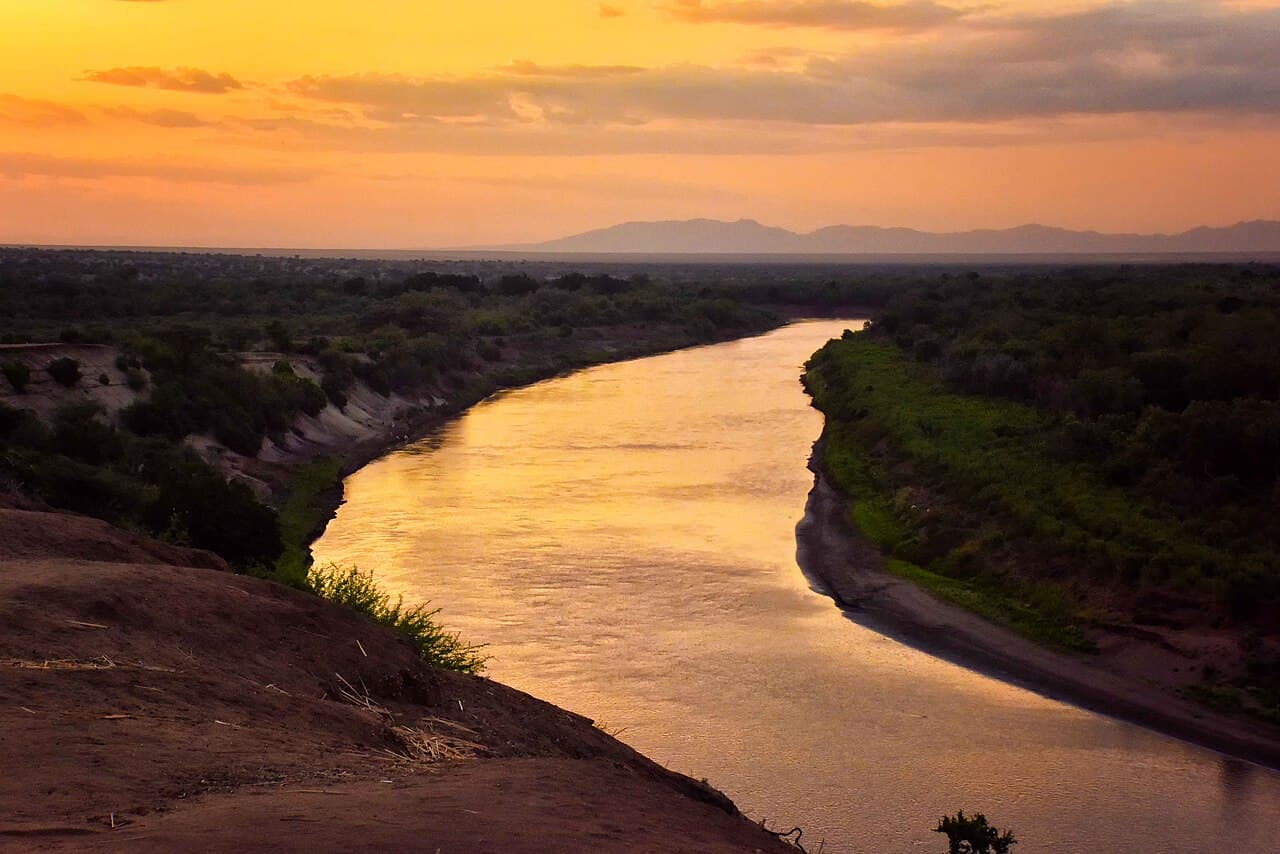 The Omo River winding through Karo land under an orange evening sky