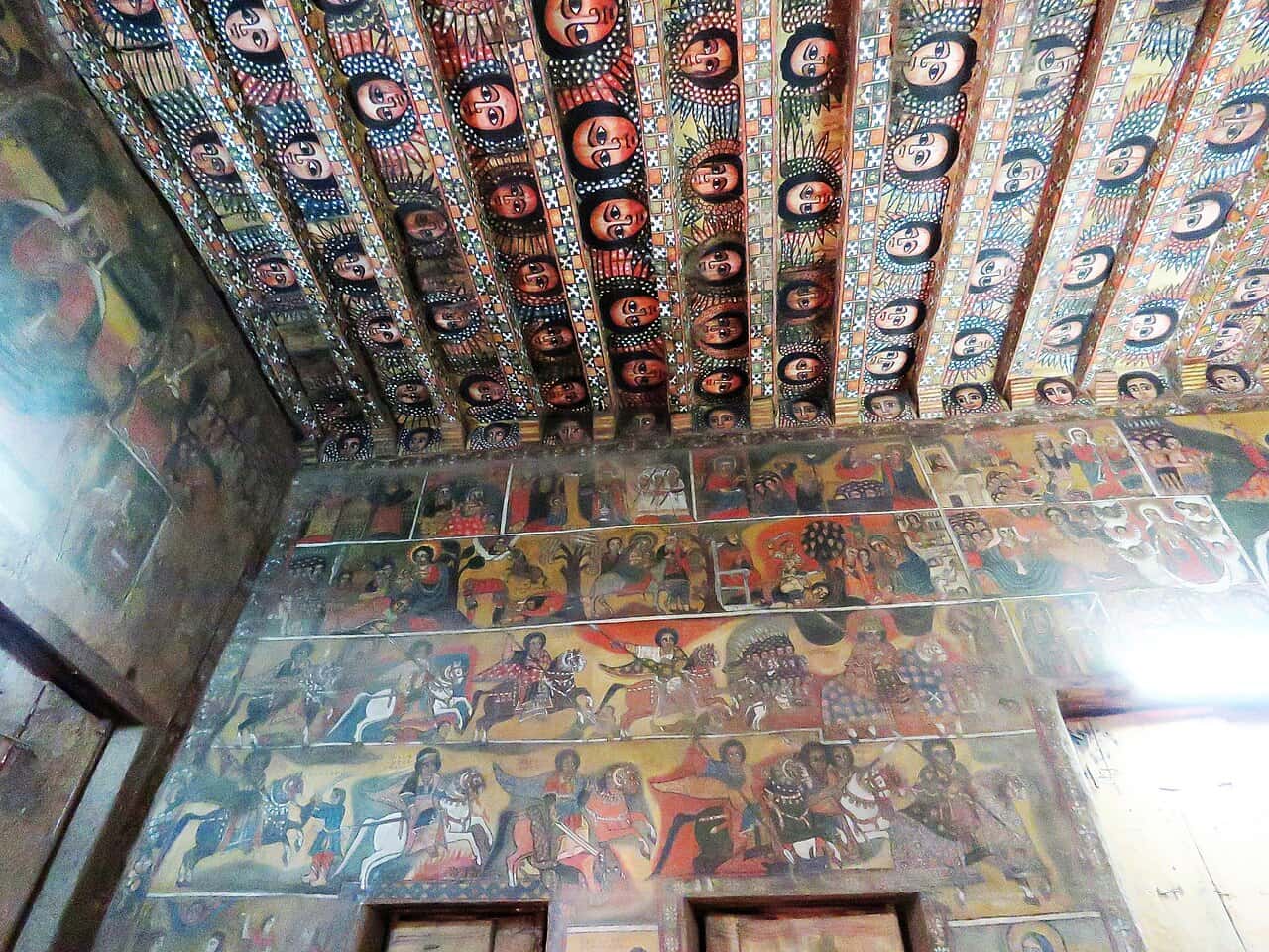 Painted angel faces on the ceiling and biblical murals on the walls of Debre Berhan Selassie Church